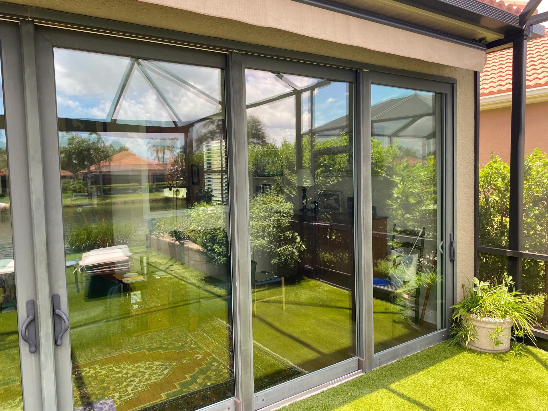 Freshly painted bronze sliding glass door frames on a screened lanai of a Sarasota home overlooking a pond