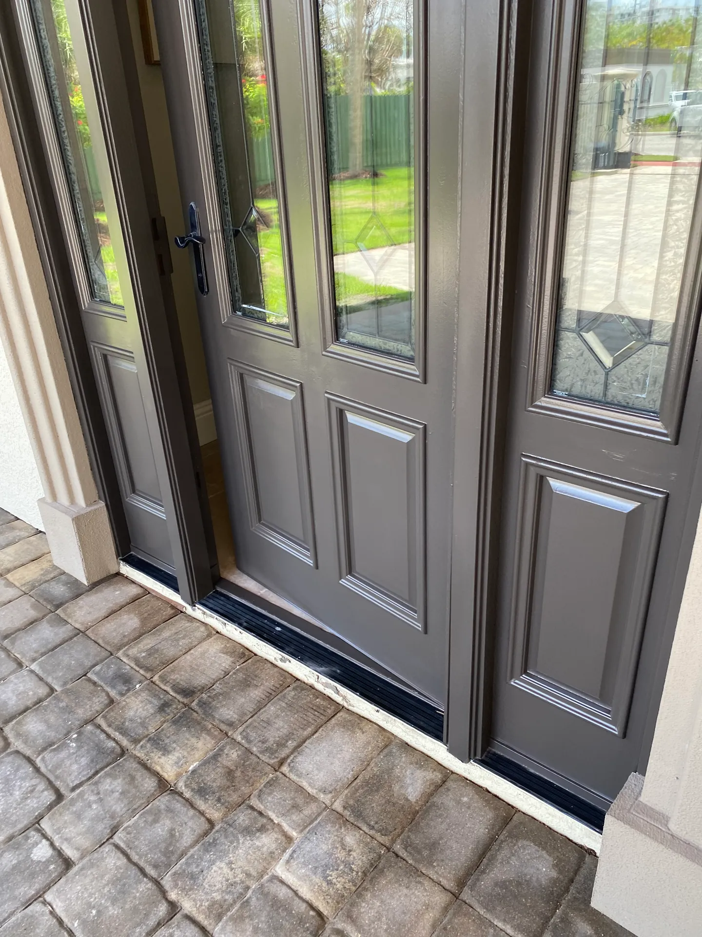Freshly painted dark bronze paneled front door with a decorative glass sidelight on a Florida home